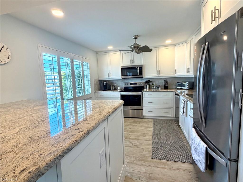 105 Penny Lane, Unit 5 Naples, FL 34112 - Photo 4 of 15 a kitchen with stainless steel appliances granite countertop a stove a sink dishwasher a refrigerator and a oven with wooden floor