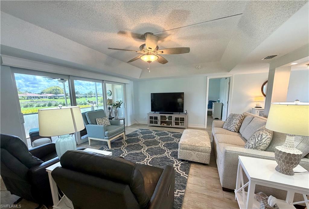 105 Penny Lane, Unit 5 Naples, FL 34112 - Photo 6 of 15 a living room with furniture a flat screen tv and a large window