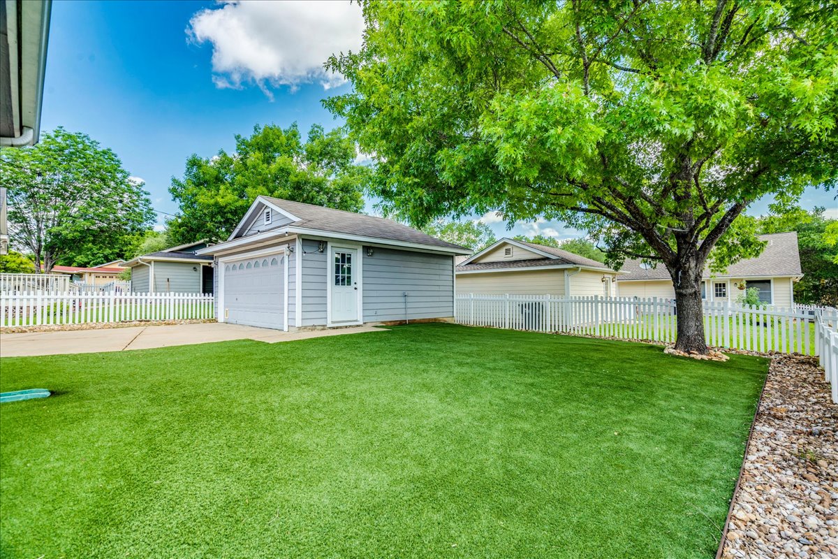 175 Wetzel Kyle, TX 78640 - Photo 5 of 27 A well-maintained lawn with a detached garage and classic white picket fencing defines this charming backyard.