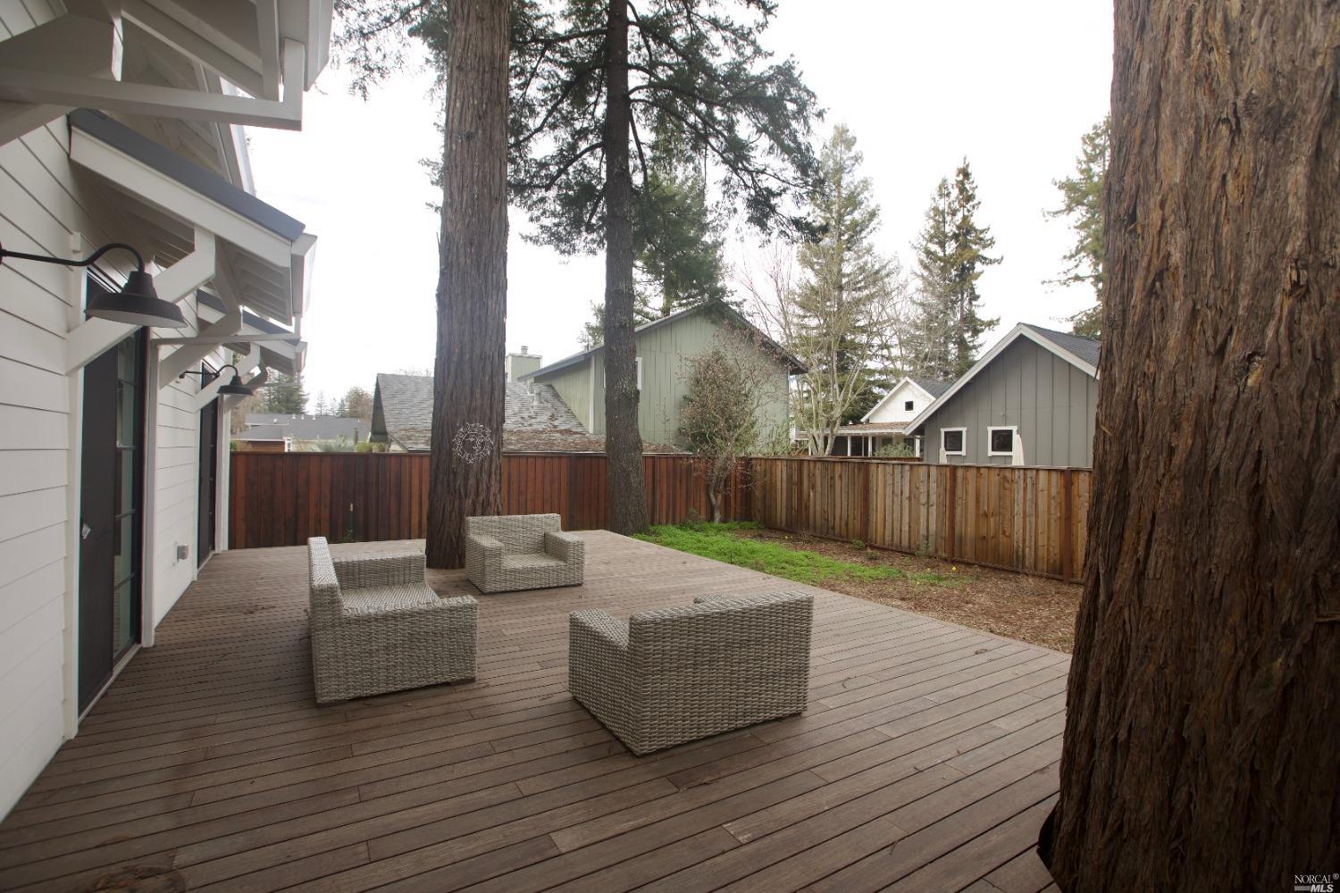a backyard of a house with wooden floor and outdoor seating