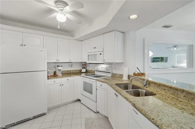 a kitchen with a sink white cabinets and white appliances