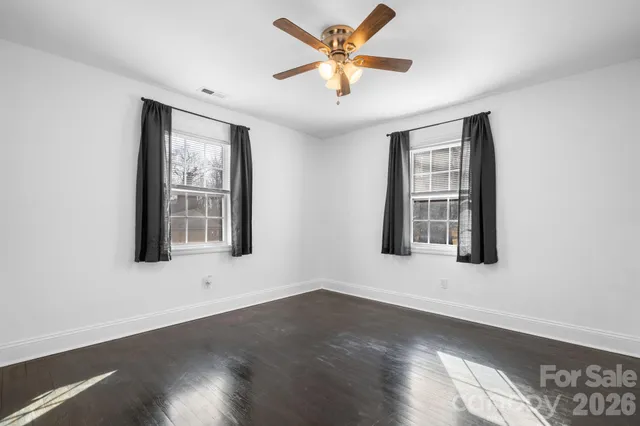 a view of an empty room with window and wooden floor