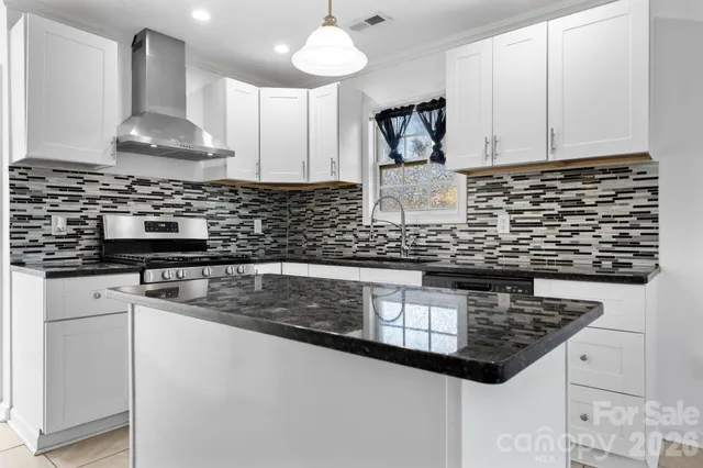 a kitchen with stainless steel appliances granite countertop a sink stove and white cabinets