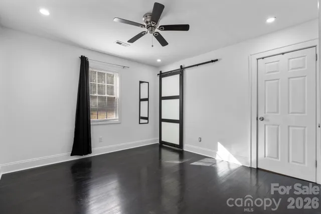 a view of an empty room with wooden floor and a ceiling fan