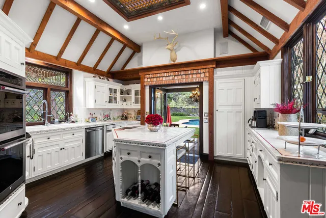 a kitchen that has a lot of white cabinets and wooden floor