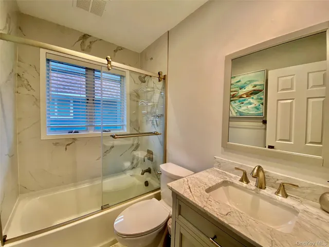 a bathroom with a granite countertop sink toilet a mirror and shower