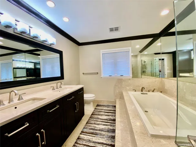 a spacious bathroom with a double vanity sink a large mirror and bathtub