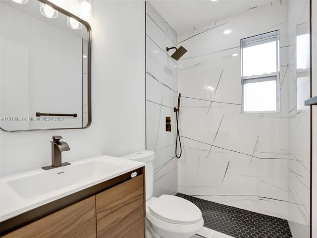 a bathroom with a sink a toilet a mirror and shower