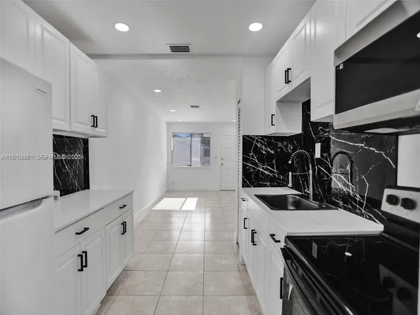 a kitchen with granite countertop a stove a sink and a microwave