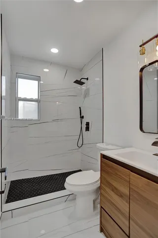 a bathroom with a granite countertop toilet a sink and a mirror