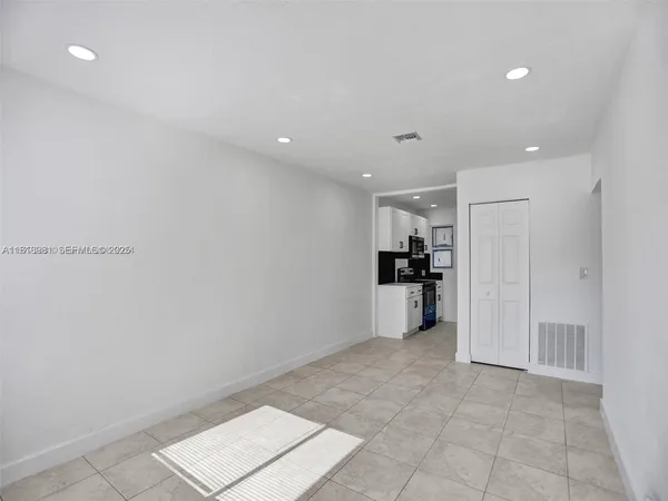 a view of a kitchen with refrigerator and white cabinets