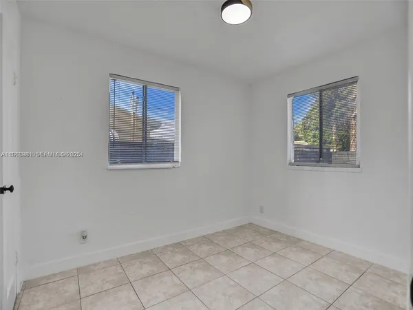 an empty room with white walls and windows