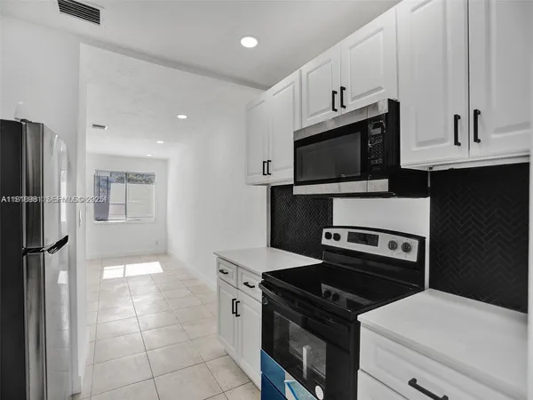 a kitchen with white cabinets and stainless steel appliances
