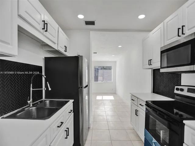 a kitchen with white cabinets and stainless steel appliances