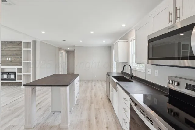 a large kitchen with stainless steel appliances granite countertop a stove a sink and a microwave