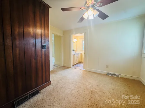 an empty room with chandelier fan and closet