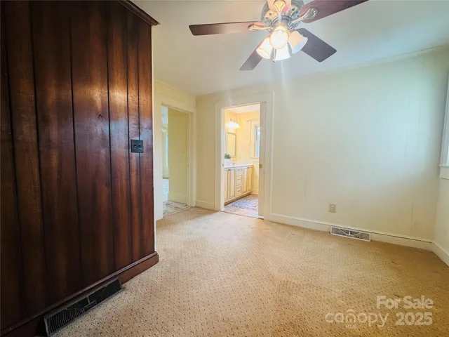 an empty room with chandelier fan and closet