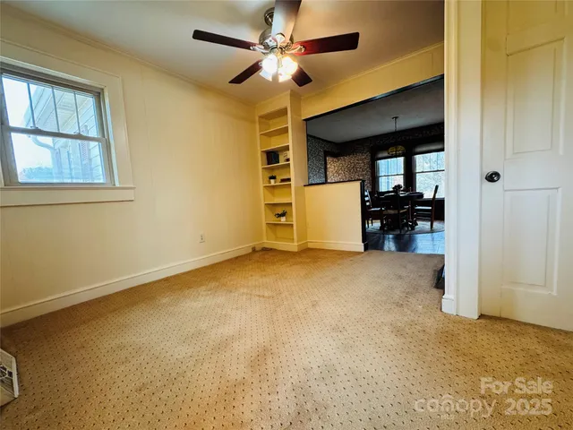 an empty room with chandelier fan and windows