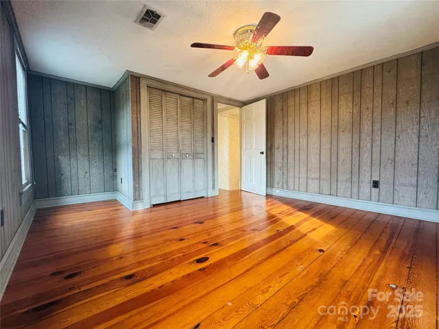 a view of room with wooden floor and a ceiling fan