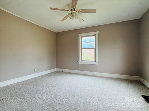 an empty room with a chandelier fan and windows