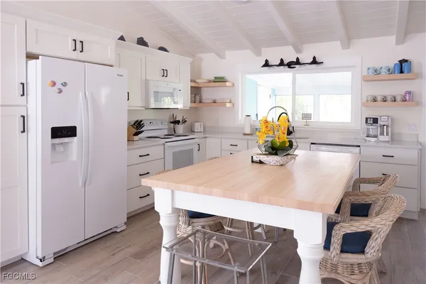 a kitchen with stainless steel appliances a white refrigerator a stove a dining table and chairs with wooden floor