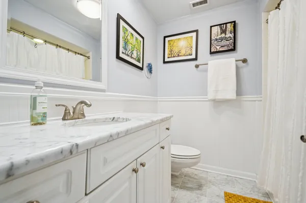 a bathroom with a granite countertop sink and a toilet