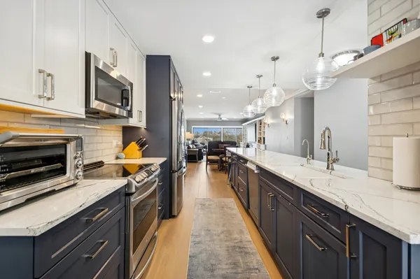 a kitchen with stainless steel appliances granite countertop a sink a stove top oven a counter space and cabinets