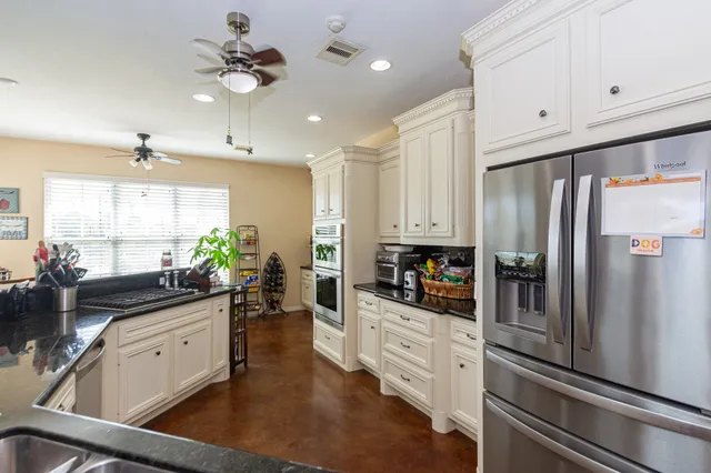 a kitchen with stainless steel appliances granite countertop a table chairs stove and cabinets