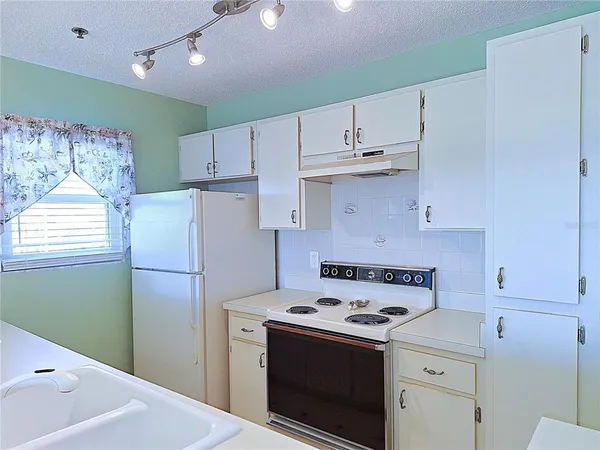 a kitchen with a refrigerator a stove and white cabinets