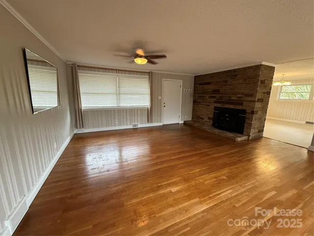 an empty room with wooden floor fireplace and windows
