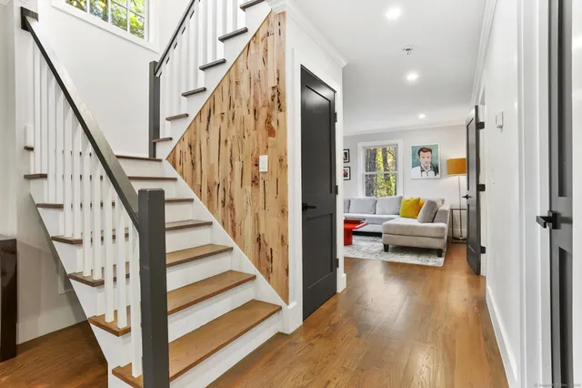 a view of a hallway to a livingroom with wooden floor and staircase