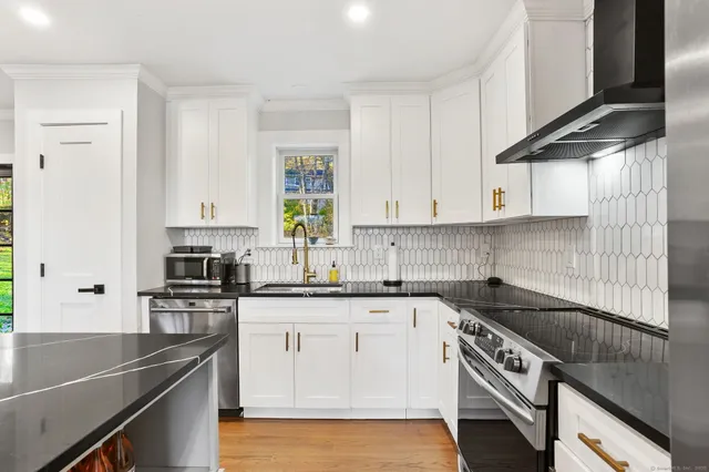a kitchen with stainless steel appliances granite countertop a sink a stove and cabinets