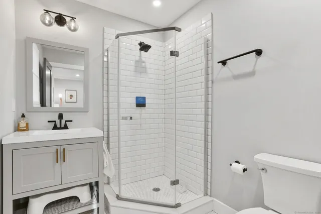 a bathroom with a shower sink vanity and toilet