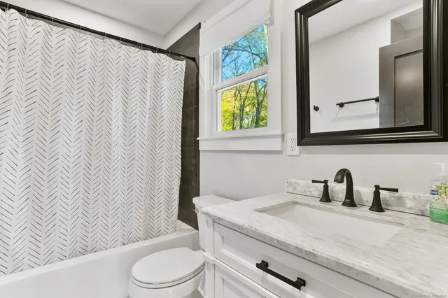a bathroom with a granite countertop sink and a toilet