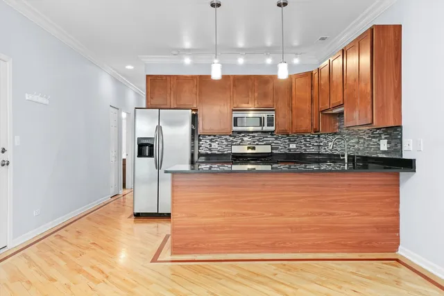 a kitchen with stainless steel appliances granite countertop a refrigerator a sink dishwasher a stove and a refrigerator with wooden floor