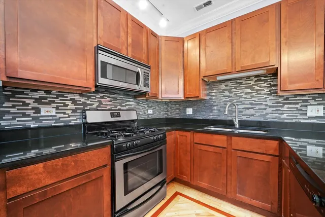 a kitchen with stainless steel appliances granite countertop wooden cabinets and a stove top oven