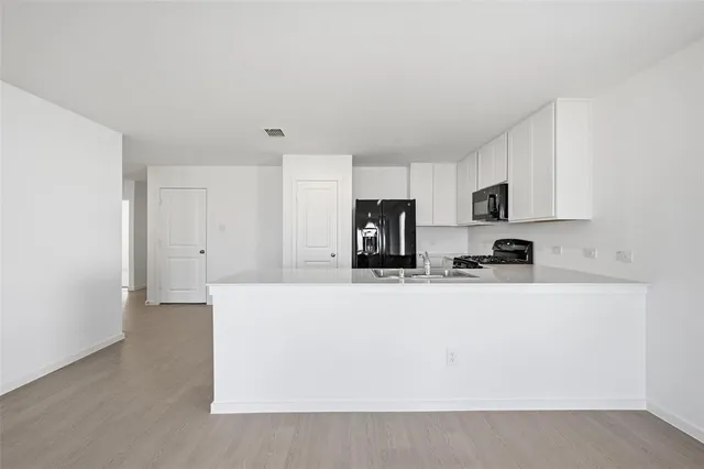 a kitchen with stainless steel appliances a refrigerator sink stove and white cabinets