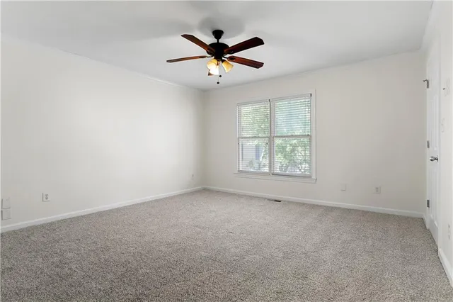 an empty room with ceiling fan and windows