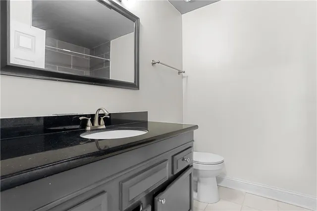 a bathroom with a granite countertop toilet sink and mirror