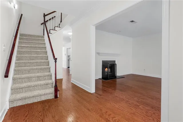 a view of an empty room with wooden floor and stairs