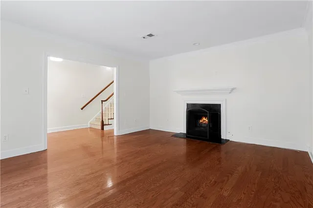 a view of an empty room with wooden floor fireplace and a window