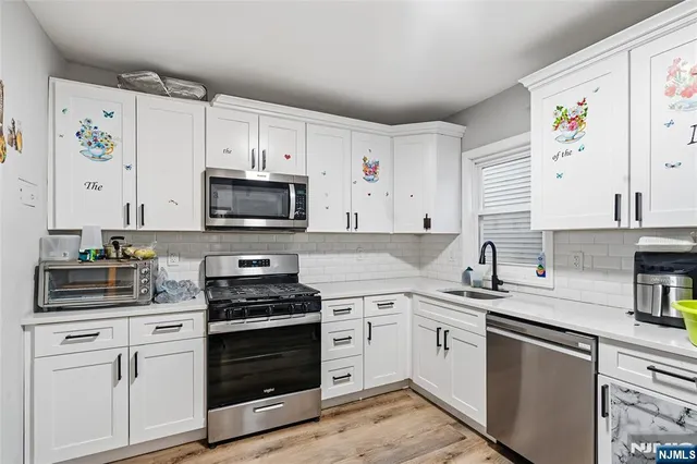 a kitchen with cabinets stainless steel appliances and wooden floor