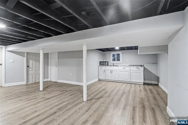a view of kitchen with white wooden cabinets and wooden floor