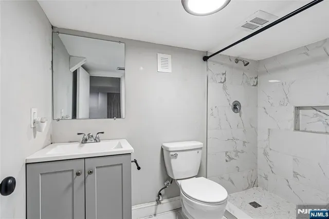 a bathroom with a toilet sink vanity and shower