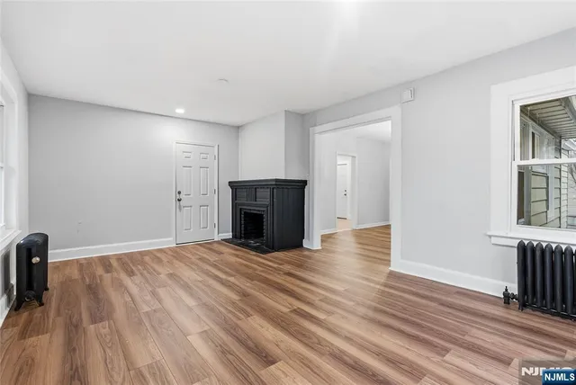 a view of empty room with wooden floor and fireplace
