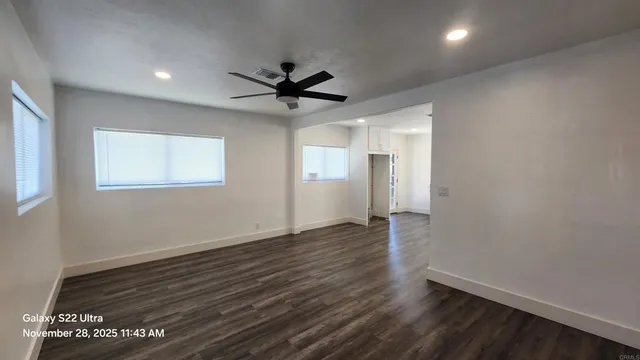 a view of empty room with wooden floor and fan