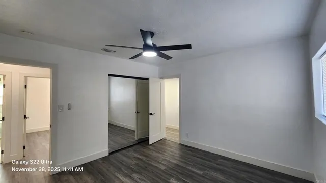 an empty room with wooden floor and a ceiling fan