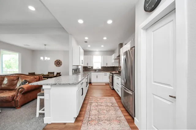 a large white kitchen with stainless steel appliances granite countertop a couch and a counter top space