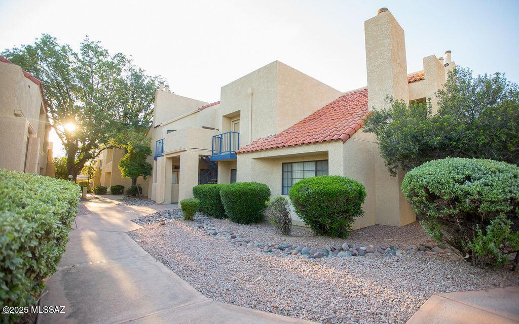 1200 East River Road, Unit B27 Tucson, AZ 85718 - Photo 39 of 40 a view of a house with a yard and table and chairs under an umbrella