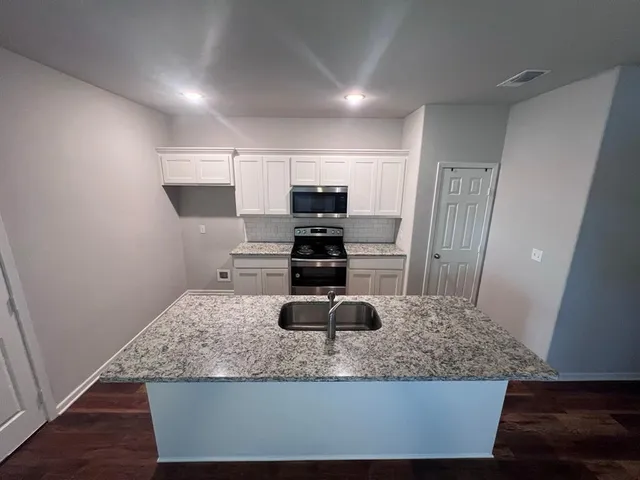 a kitchen with kitchen island granite countertop a sink a stove and a refrigerator